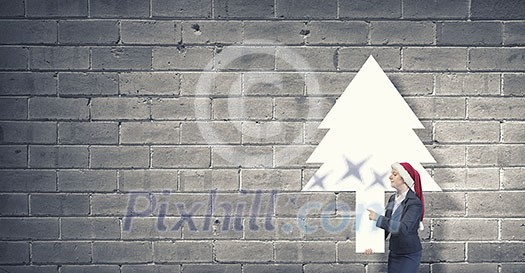 Woman in Santa hat pointing with finger at blank banner. Place for your text