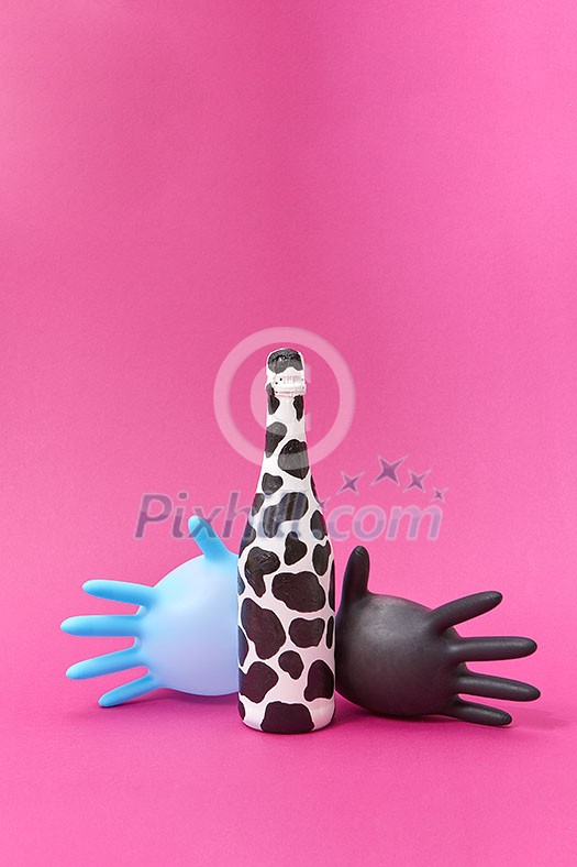 Creative composition with painted wine bottle of black spots and two rubber surgical balloon gloves on a hot pink background, copy space.