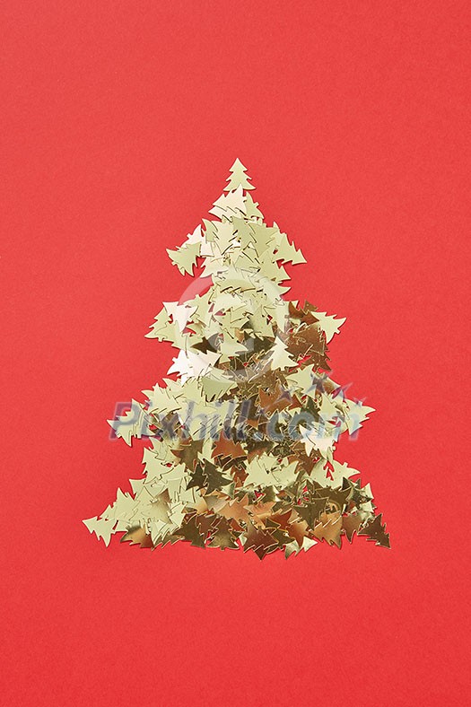New Year decorative tree handmade from shiny small spruces on a red background, copy space. Greeting holiday card.