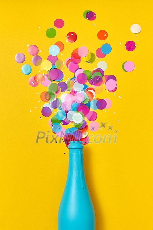 Christmas champagne blue painted with glitter confetti as a drink bubbles on an yellow background, copy space. Flat lay.