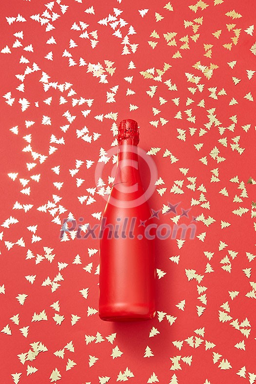 Christmas red painted champane bottle mock up on a holiday background covered shiny small spruces with copy space. Greeting holiday card.