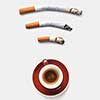 Three roach cigaretts around a cup of coffee as a wireless simbol on a light grey background with copy space. Concept of addiction from smoking and gadgets.