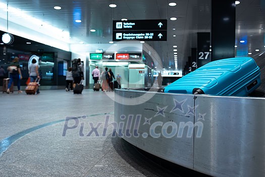 Arrived luggage going around on a conveyor belt waiting to be claimed at the baggage claim zone at a modern international airport