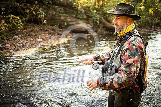 Fly fisherman working the line and the fishing rod while fly fishing on a splendid mountain river for rainbow trout Fly fisherman working the line and the fishing rod while fly fishing on a splendid mountain river for rainbow trout