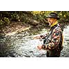 Fly fisherman working the line and the fishing rod while fly fishing on a splendid mountain river for rainbow trout