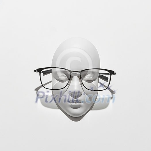 Elegant glasses on a gypsum face sculpture with shadows on a white background, copy space. Glasses for reading and person with visual impairment. Top view. Elegant glasses on a gypsum face sculpture with shadows on a white background, copy space. Glasses for reading and person with visual impairment. Top view.