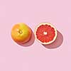 Halves juicy grapefruit presented on a pink background with reflection of shadow and copy space. Dietetic food. Top view