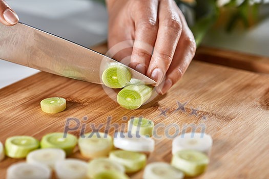 Slices of leek on a wooden board. Hands of the girl cut vegetables on the kitchen table. Cooking healthy food. Slices of leek on a wooden board. Hands of the girl cut vegetables on the kitchen table. Cooking healthy food.
