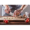 On a wooden table, the hands of a woman cut quail eggs on an old wooden board. Step by step salad preparation