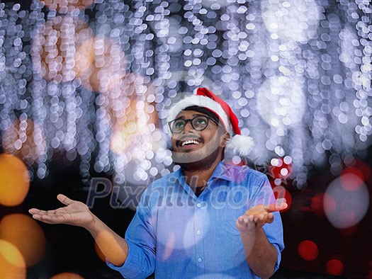 Indian man wearing traditional Santa Claus hat on chalkboard  background studio dark-skinned Christmas santa new year party