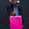 Indian  man wearing party clothes in Santa hat with shopping bag on dark  background studio dark skinned middle eastern Santa Claus merry Christmas