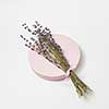 Natural branch of lavender flowers on a round board on a light grey background with copy space. Creeting card.