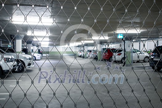 Gated underground parking. Cars parked in a garage with no people. Many cars in parking garage interior. Underground parking with cars (color toned image) Gated underground parking. Cars parked in a garage with no people. Many cars in parking garage interior. Underground parking with cars (color toned image)