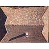 Old tile roof above the house with high chimney and hard shadows from sunny in a summer day. Aerial top view from drone.