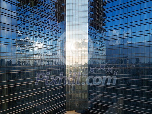 Aerial shot of modern office building windows, reflection of cityscape on a sunny day.
