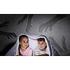 Children sitting in bed under blanket with book