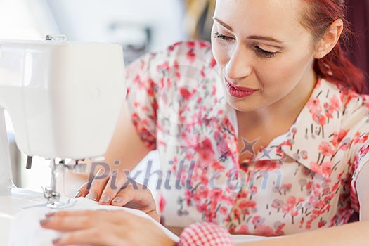 Young attractive woman dressmaker working with sewing machine