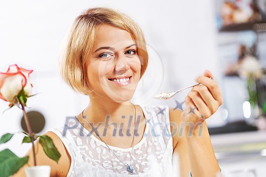 Portrait of young pretty woman sitting at cafe and eating dessert Portrait of young pretty woman sitting at cafe and eating dessert
