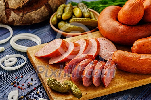 Sliced sausage on a cutting board. Smoked meat products on a wooden table. Food still life in a rustic style. Sliced sausage on a cutting board. Smoked meat products on a wooden table. Food still life in a rustic style.