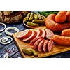 Sliced sausage on a cutting board. Smoked meat products on a wooden table. Food still life in a rustic style.