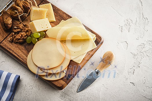 Different varieties of cheese with grapes and walnuts on a wooden board Different varieties of cheese with grapes and walnuts on a wooden board