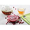 Cranberry jam in a glass bowl and teapot on a white background