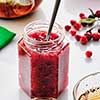 Cranberry jam in a glass jar and teapot on a white background