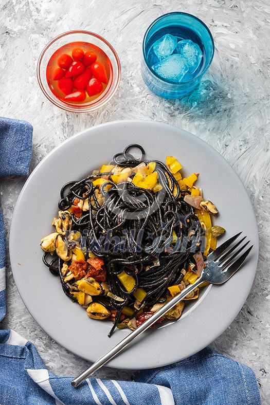 Black pasta with seafood, anchovies, tomatoes and bell peppers. Top view. Black pasta with seafood, anchovies, tomatoes and bell peppers. Top view.