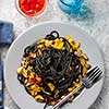 Black pasta with seafood, anchovies, tomatoes and bell peppers. Top view.