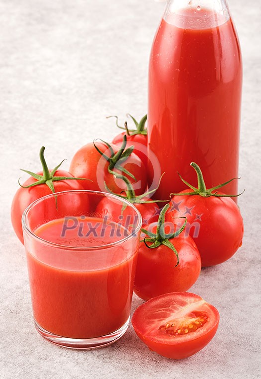 Tasty Tomato juice in a glass with ripe red tomatoes