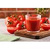 Tasty Tomato juice in a glass with ripe red tomatoes