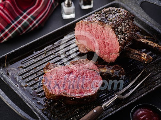 Grilled piece of meat with bone in a grill pan. Fried steak. Roasting - Medium Rare.