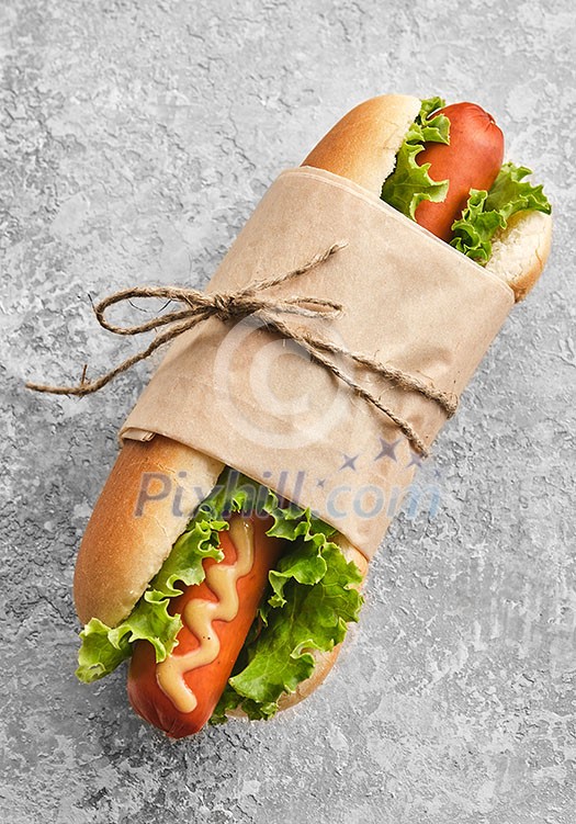 Hot dog with mustard in craft paper, top view. Hot dog with mustard in craft paper, top view.