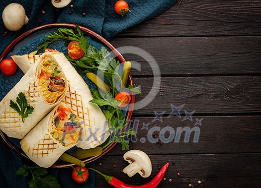 Shaurma, shawerma, fajita served on wooden table. Mediterranean cuisine. Copy space, top view. Shawarma with spiced, cherry tomato and bell pepper