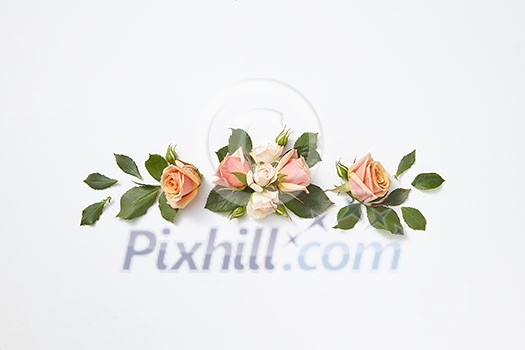 Decoration from beautiful roses flowers with green leaves on a light grey background, copy space. Congratulation card for birthday.
