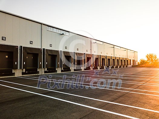 Warehouse exterior with loading ramps and slots for trucks to park - modern industry warehouse storage building.