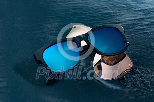 Modern sun glasses on a dark blue background with copy space. Modern accessory for protection eyes. Modern sun glasses on a dark blue background with copy space. Modern accessory for protection eyes.