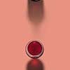 Top view above opened bottle and glass of red wine on a pastel coral background with soft dark shadows, copy space