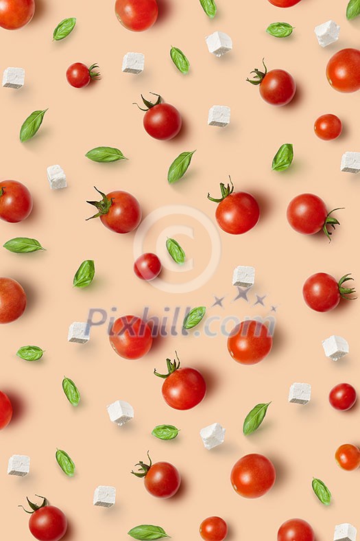Vegetable pattern from freshly picked natural organic ripe healthy tomatoes cherry, basil leaves and cheese cubes on a beige background. Top view.
