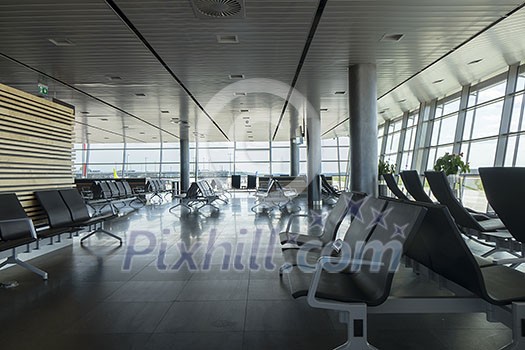 Modern airport waiting hall interior with empty chairs in departure area. Travel and transportation concept.