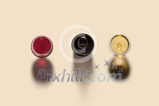 Top view on alcohol drink set with two glasses of red and white wine and opened bottle with dark shadows on a light beige background, copy space.
