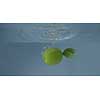 Natural ripe fresh lime with green leaf is swimming under water in a glass container on a grey background. Slow motion 2K video.