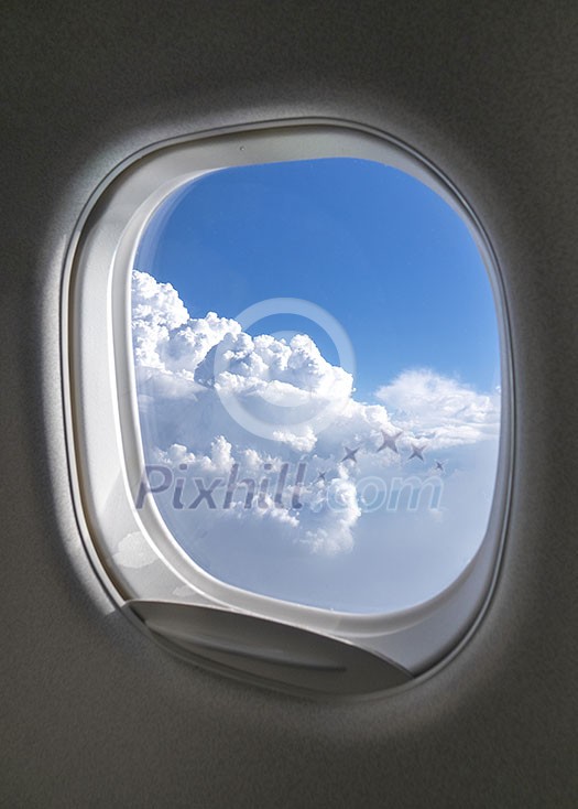 Aircraft windows frame with beautiful aerial view of clear blue cloudy sky lighted sunny beams with copyspace. Travel and transportation concept.
