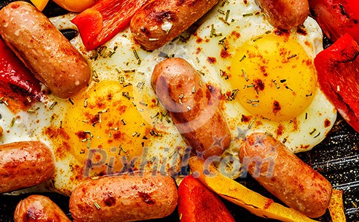 Fried eggs with sausages and sweet peppers, close-up, top view. Fried eggs with sausages and sweet peppers, close-up, top view.