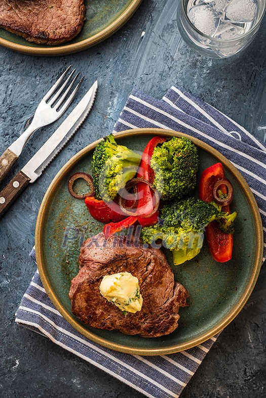 Grilled Beef steak with garlic butter and vegetables. Meat with grilled bell pepper, broccoli and onions. View above.