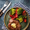 Grilled Beef steak with garlic butter and vegetables. Meat with grilled bell pepper, broccoli and onions. View above.