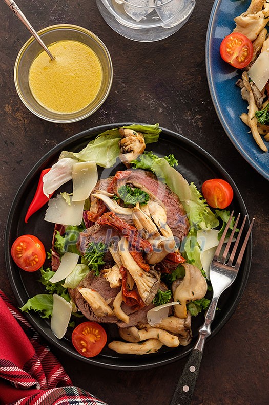Salad with warm beef with oyster mushrooms, tomatoes and greens. Top view. Salad with warm beef with oyster mushrooms, tomatoes and greens. Top view.