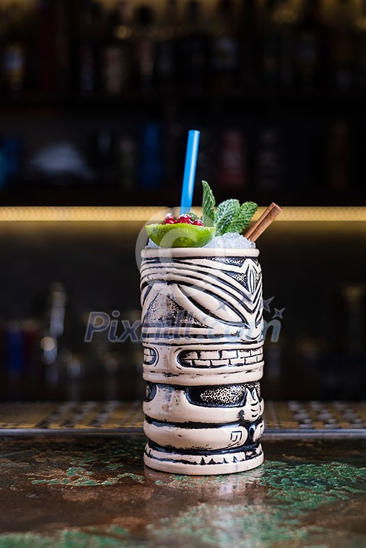 Alcoholic cocktail with lime, pomegranate and mint on a bar in a tiki bar Alcoholic cocktail with lime, pomegranate and mint on a bar in a tiki bar