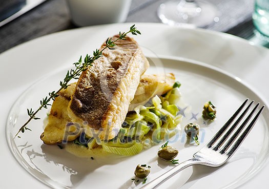 Fillet of halibut on a pillow of stewed leeks on the white plate