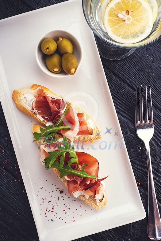 Bruschetta with Parma and goat cheese, olives and almonds. Wine set. Toned image.